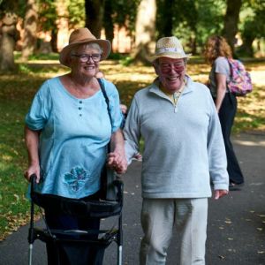 Couple de seniors souriants en balade dans un parc avec un déambulateur