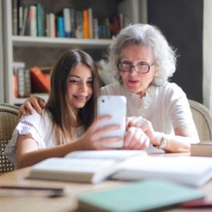 Grand-mere et petite-fille prenant un seflie avec un telephone en souriant